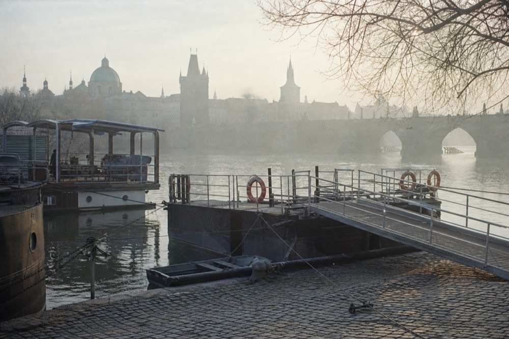 A floating gangway and boarding ramp at a Prague river pier, life rings on the rail, quiet morning light